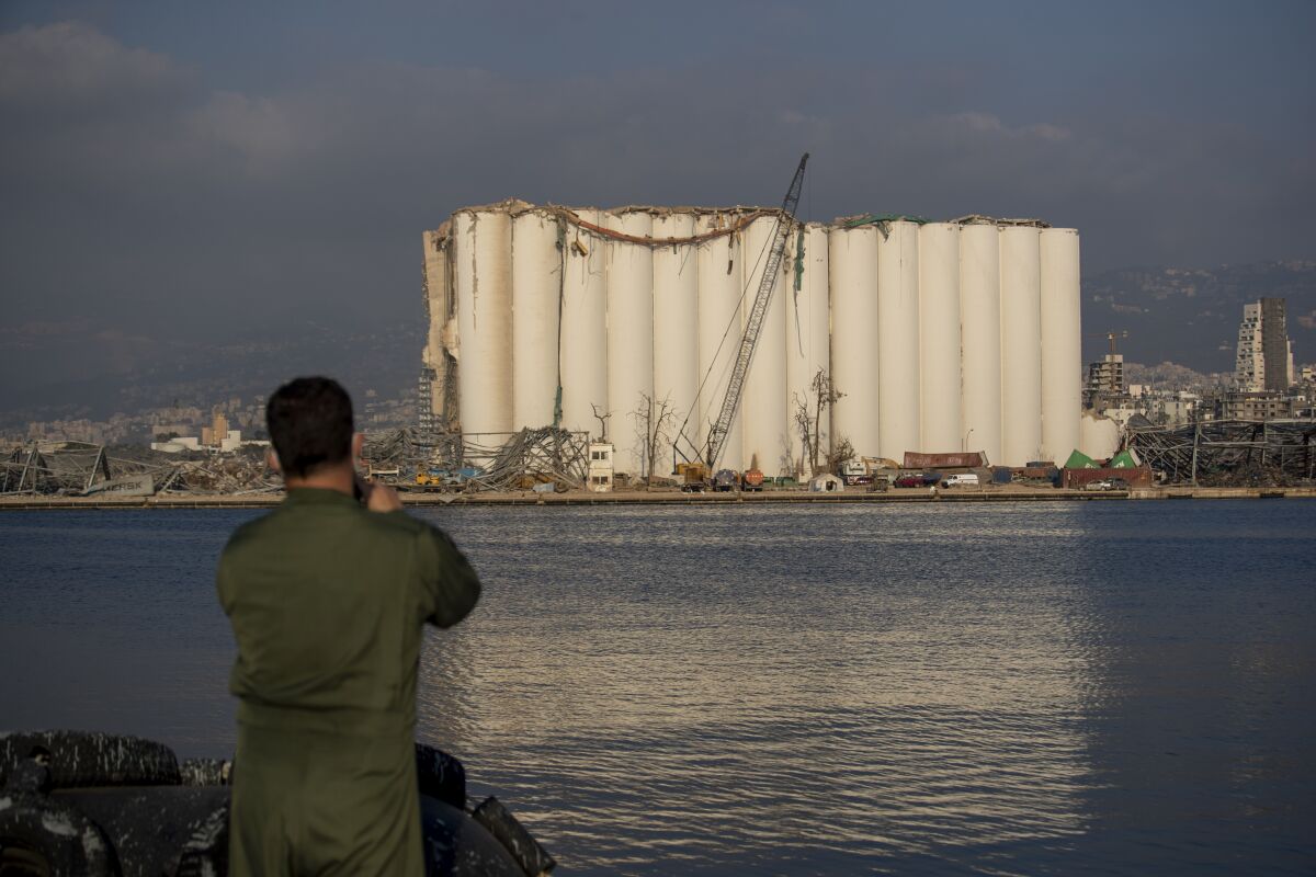 A Brazilian soldier takes a picture of a damaged silo that stands amid rubble and debris at the site of the Aug. 4 explosion that killed more than 170 people, injured thousands and caused widespread destruction, in Beirut, Lebanon, Thursday, Aug. 13, 2020. (AP Photo/Hassan Ammar)