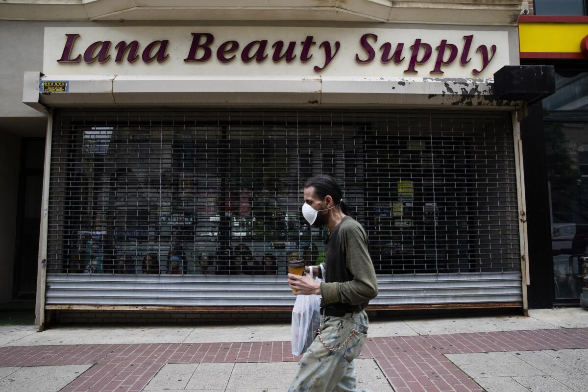 A shopper wearing a protective mask passes a shuttered beauty-supply store in Allentown, Pennsylvania.
