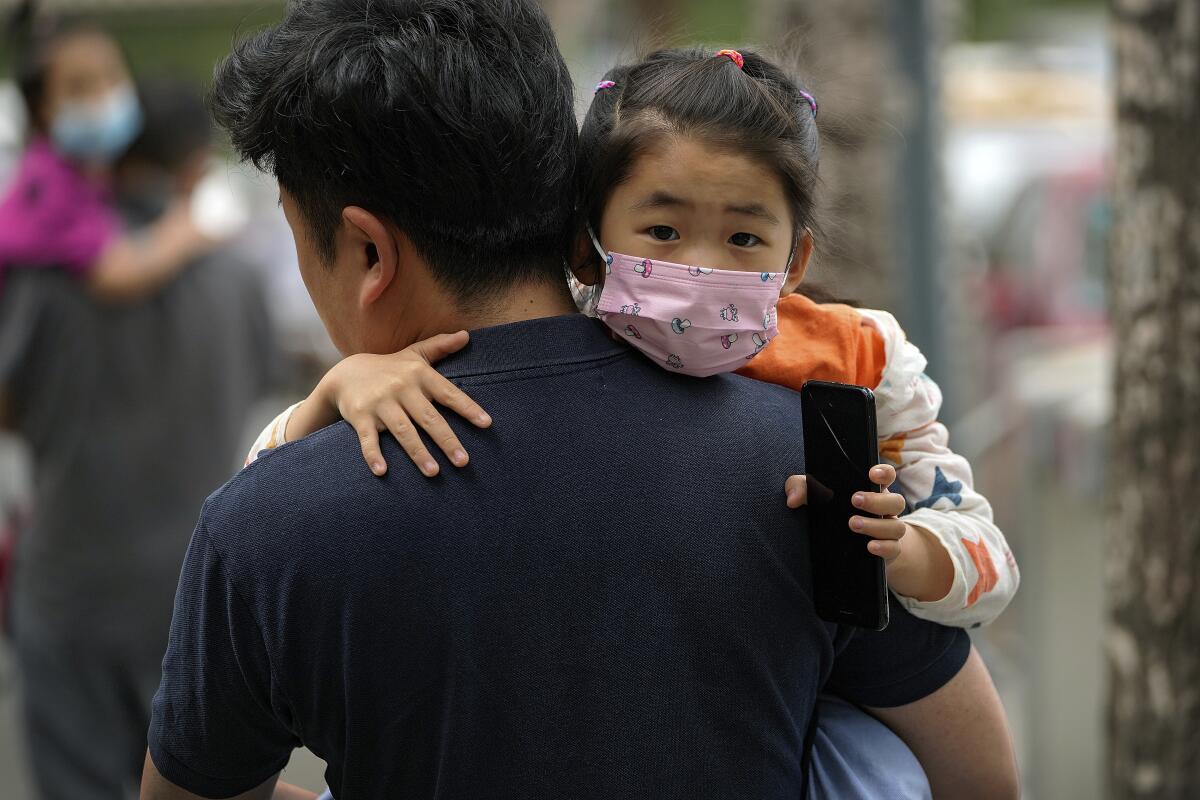 A man carries a child to a school in Beijing.