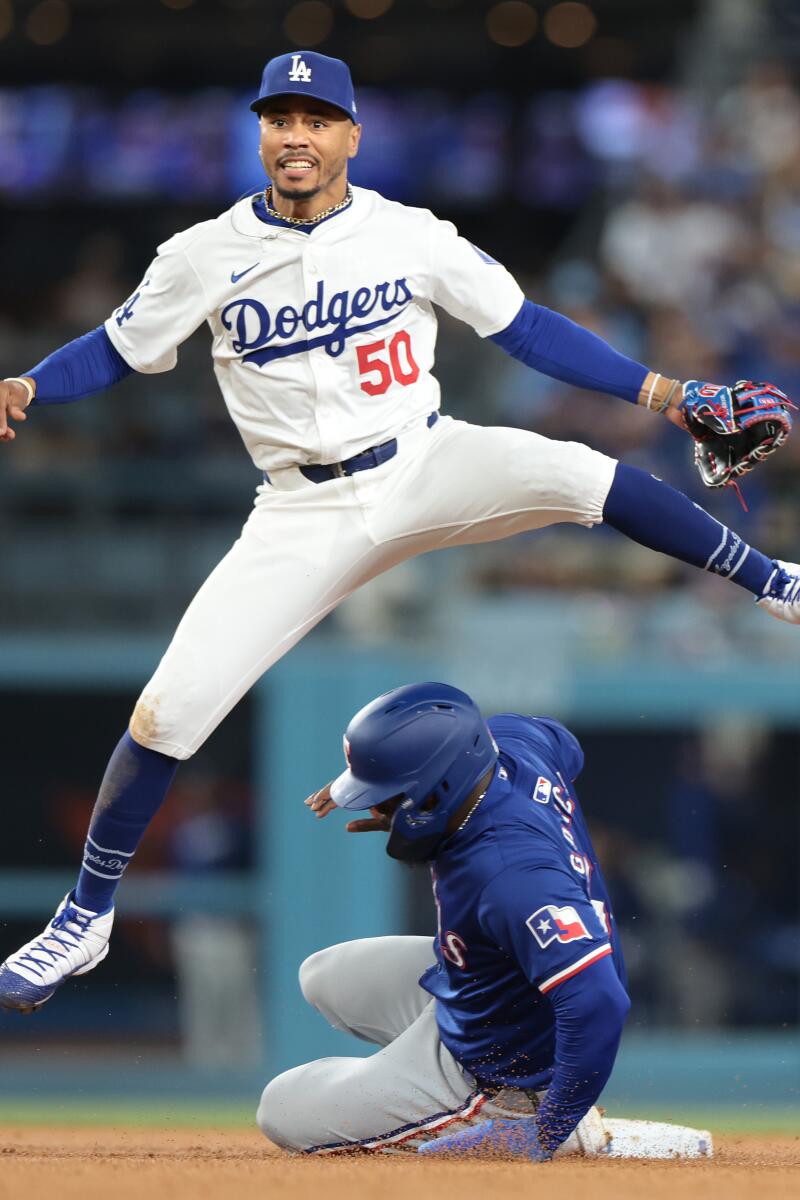 Dodgers shortstop Mookie Betts leaps over Rangers baserunner Adolis Garcia while turning a double play on June 13.