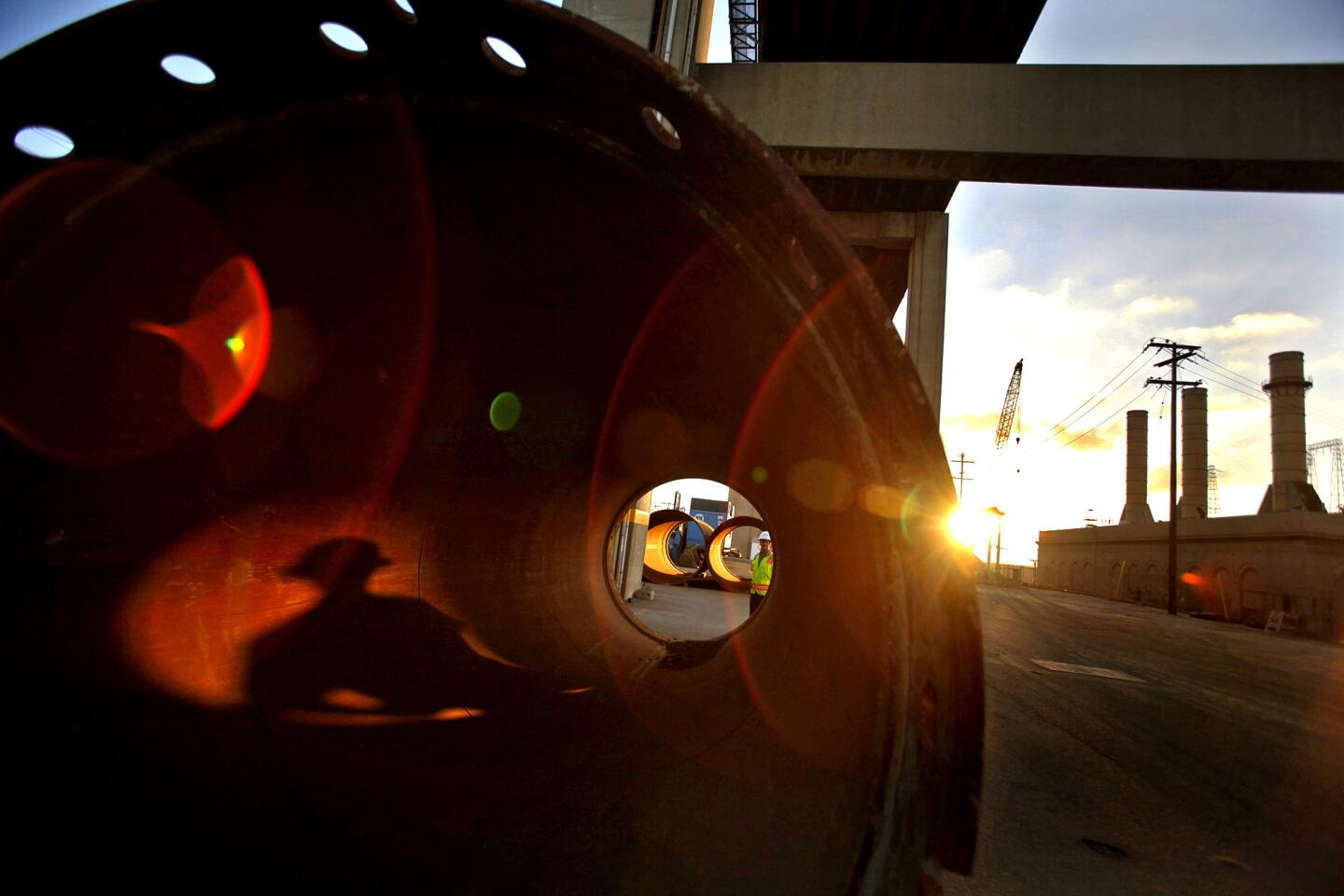 John Pope of the Port of Long Beach casts a shadow as he walks past a huge pile casing pipe, which will be used to create pylons for the construction of a new bridge from Terminal Island to Long Beach, replacing the Gerald Desmond bridge.