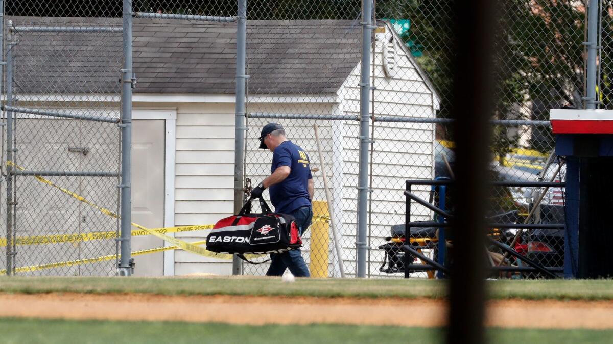 An FBI investigator removes a baseball bag from the Alexandria, VA. field where House Majority Whip Steve Scalise and others were during a congressional baseball practice.