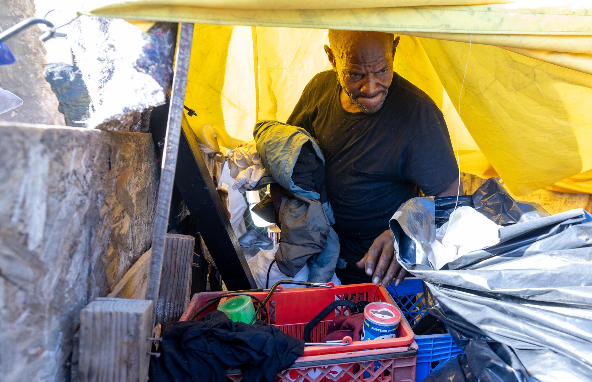 62 岁的德怀特·托马斯 (Dwight Thomas) 周三在第 86 街和百老汇的帐篷营地收拾自己的物品。