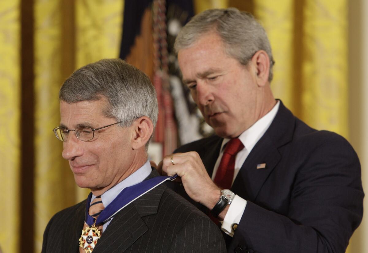 President George W. Bush puts a medal on Dr. Anthony Fauci.