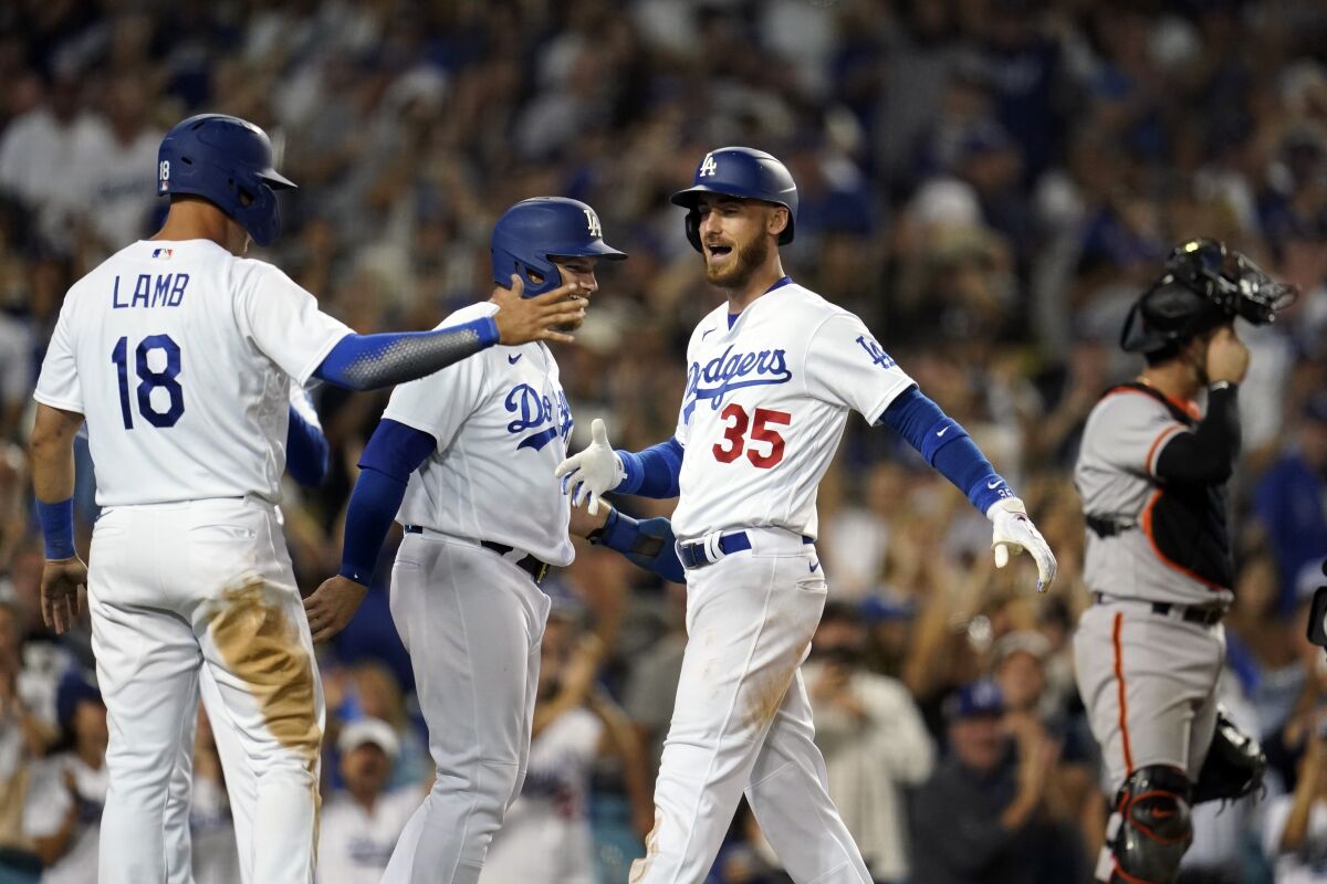 Los Angeles Dodgers' Cody Bellinger (35) celebrates his grand slam at home plate with Max Muncy and Jake Lamb (18) during the eighth inning of the team's baseball game against the San Francisco Giants on Friday, July 22, 2022, in Los Angeles. (AP Photo/Marcio Jose Sanchez)