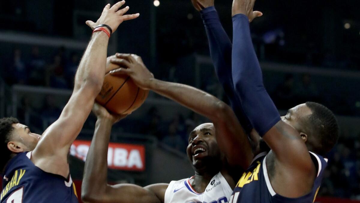 Clippers forward Luc Mbah a Moute tries to score between Nuggets guard Jamal Murray and forward Paul Millsap during a game Oct. 17.