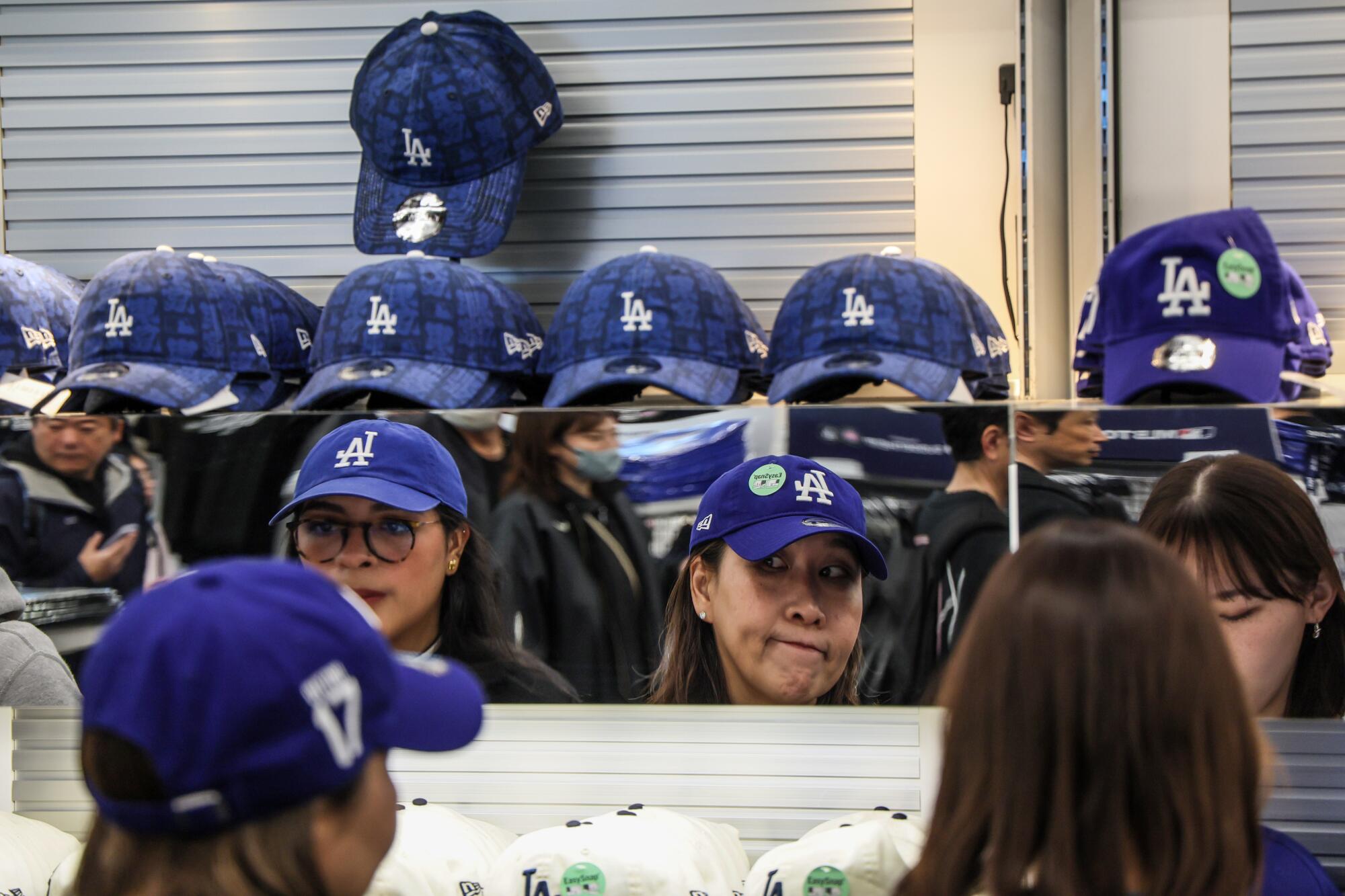 Hayranlar Cuma günü Tokyo Dome'daki bir hediyelik eşya mağazasında Dodgers Caps'ı deniyorlar.