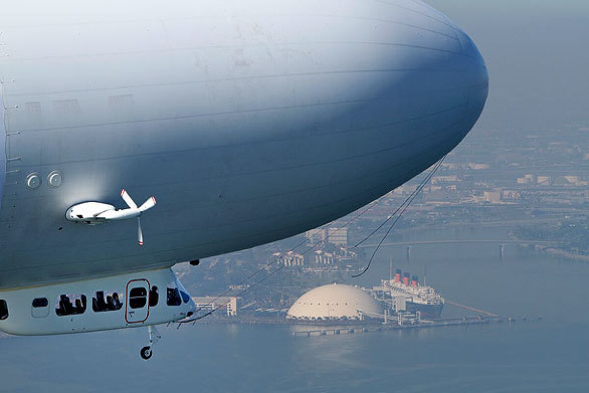 The 246-foot zeppelin Eureka, which can carry 13 passengers and a crew of two, flies over Long Beach Harbor, with the Queen Mary in the background. The German-made airship, which is filled with nonexplosive helium gas, is permanently based in the San Francisco Bay Area. It will offer a limited number of Southland scenic tours out of Long Beach Airport.