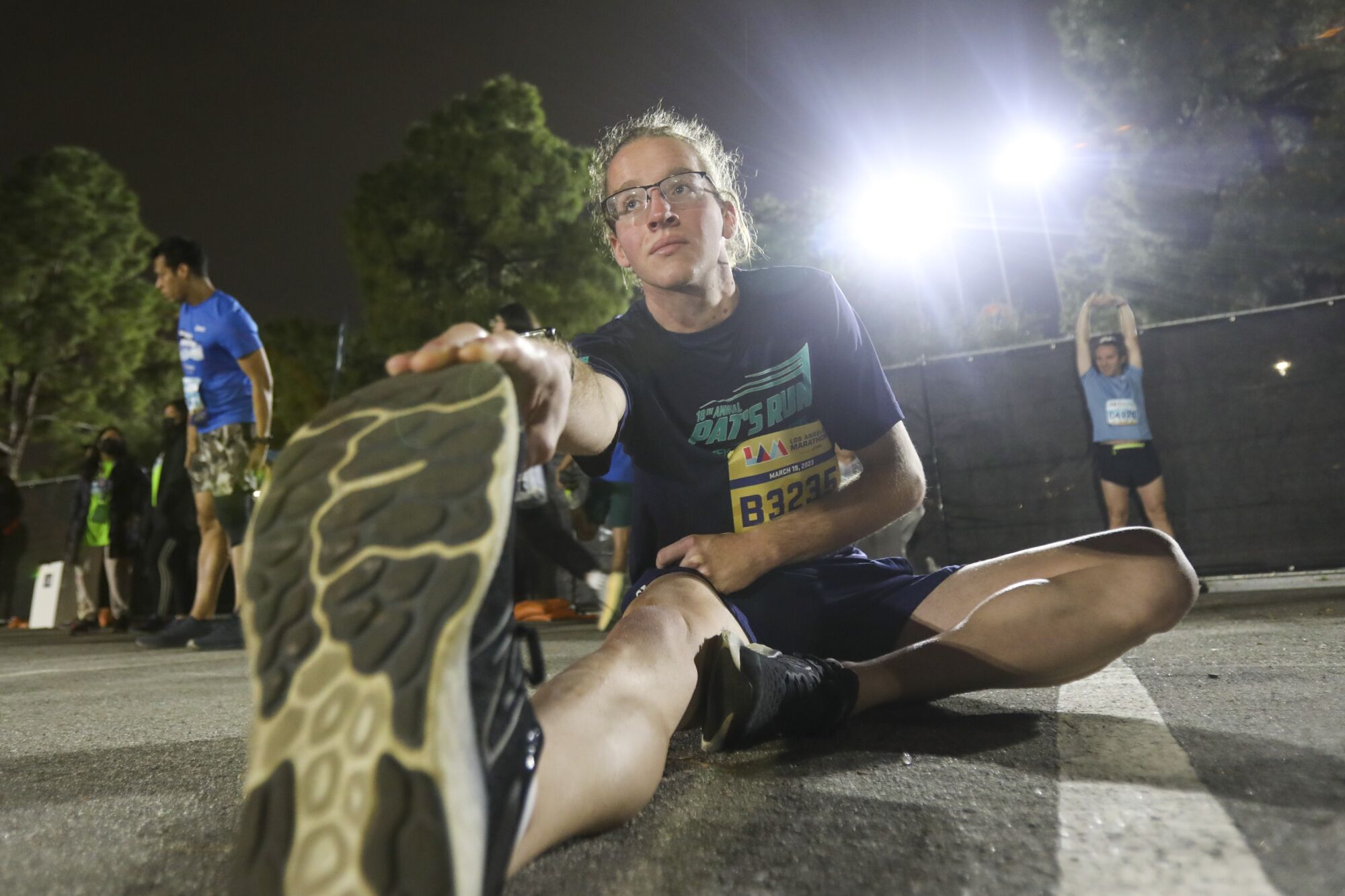 A runner stretches in the predawn darkness.