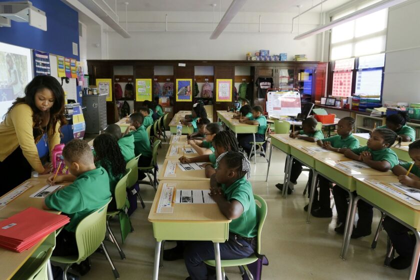 Teacher Shanel Sommers looks over the work of one of her third-graders at KIPP Thrive Academy, a new school in what had been the closed Eighteenth Avenue School, Wednesday, Sept. 9, 2015, in Newark, N.J. When Facebook founder Mark Zuckerberg appeared on Oprah Winfrey’s show five years ago with a Democratic mayor and Republican governor to announce a $100 million donation to try to remake the education system in Newark, it was presented as an effort to make a struggling city into a national model for turning around urban schools systems. Thanks to Zuckerberg’s money and another $100 million in matching donations, thousands of children have switched to publicly funded charter schools, where educational outcomes have generally been better for students. But the sped-up exodus has left traditional public schools in an ever-worsening financial condition and there’s been no marked improvement in performance for the students left there; by several measures, there have been declines. (AP Photo/Mel Evans)