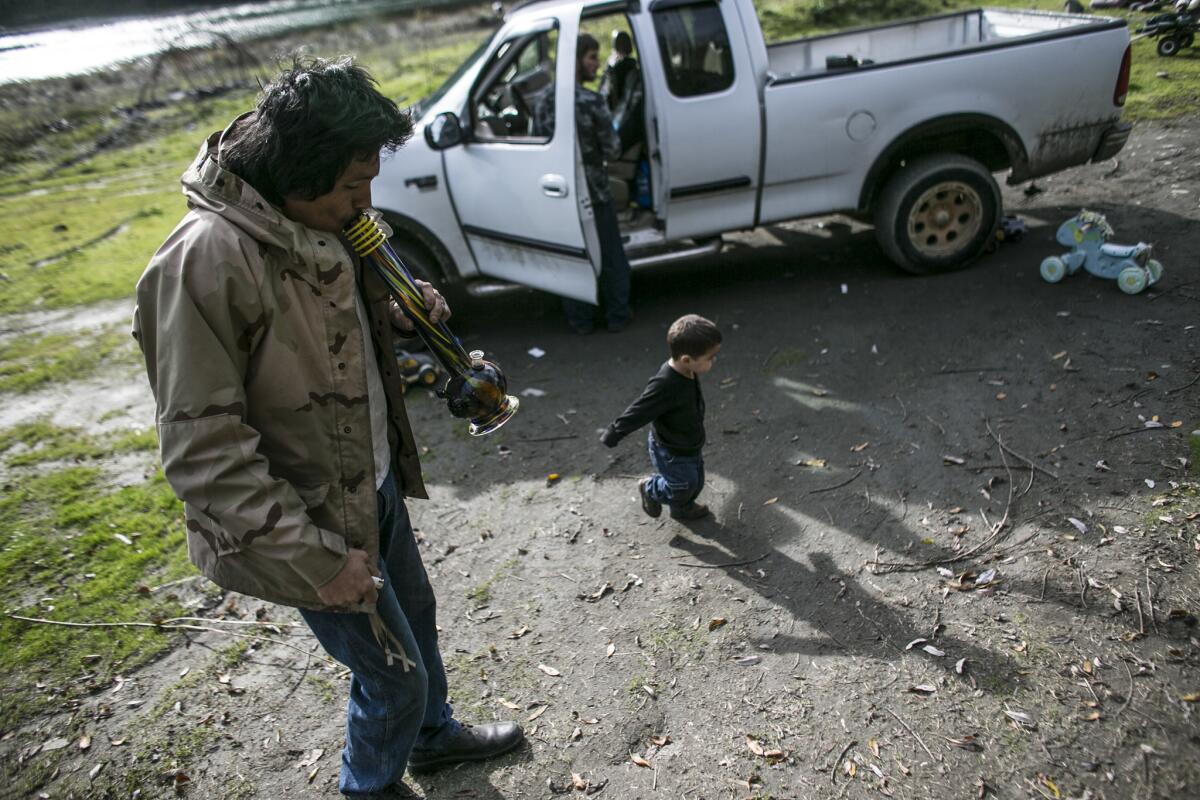 Louie Myers smokes marijuana from a bong as his grandson, Jared Osburne, 2, plays nearby.