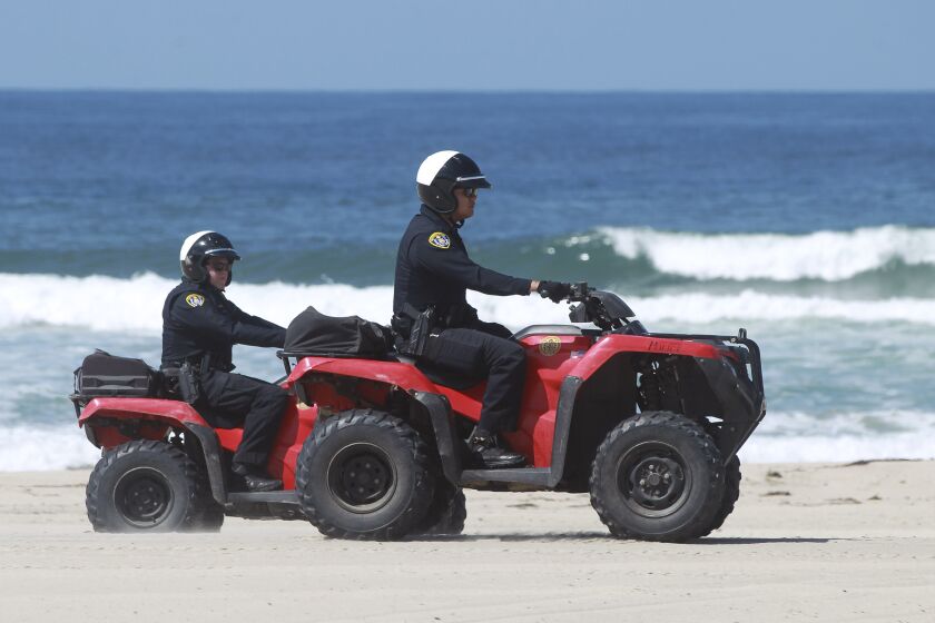 A pair of San Diego police officers ride all terrain vehicles on Mission Beach, which is closed due to the coronavirus outbreak, on Saturday March 28, 2020 in San Diego, California.