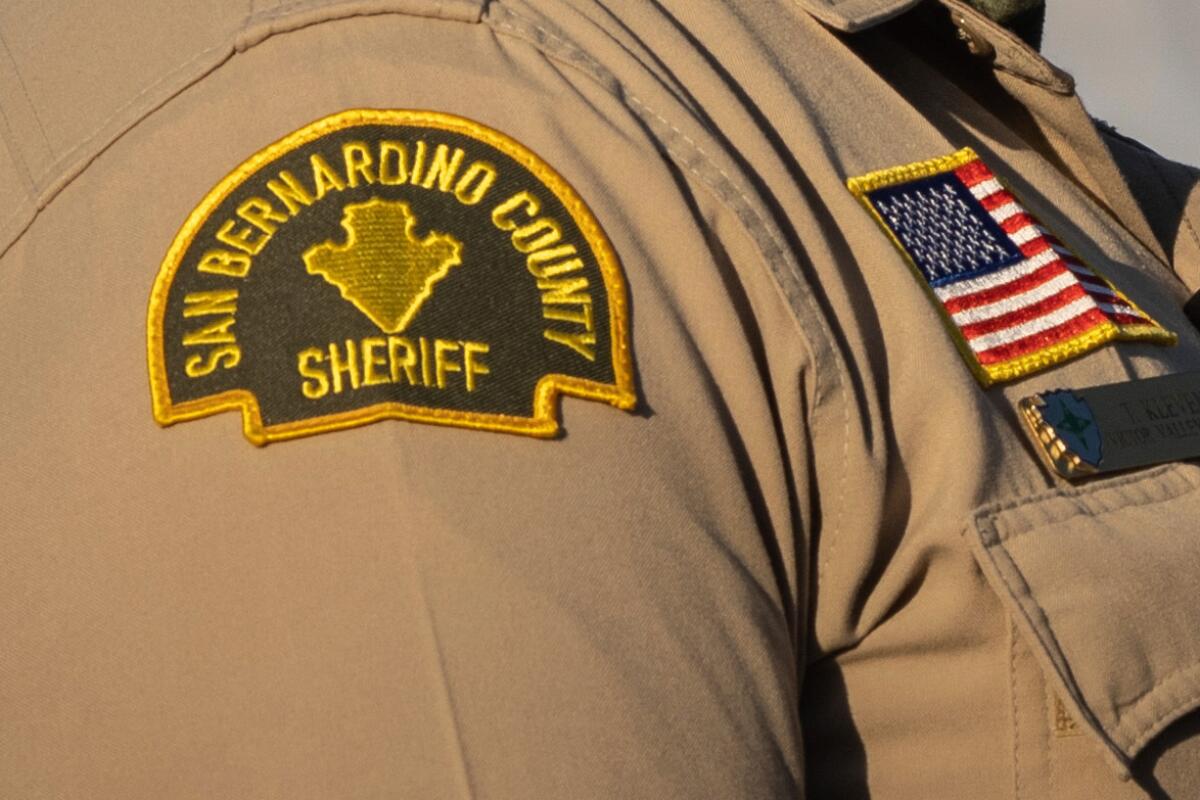 Closeup of the shoulder of a uniformed person; the badge reads "San Bernardino County sheriff."