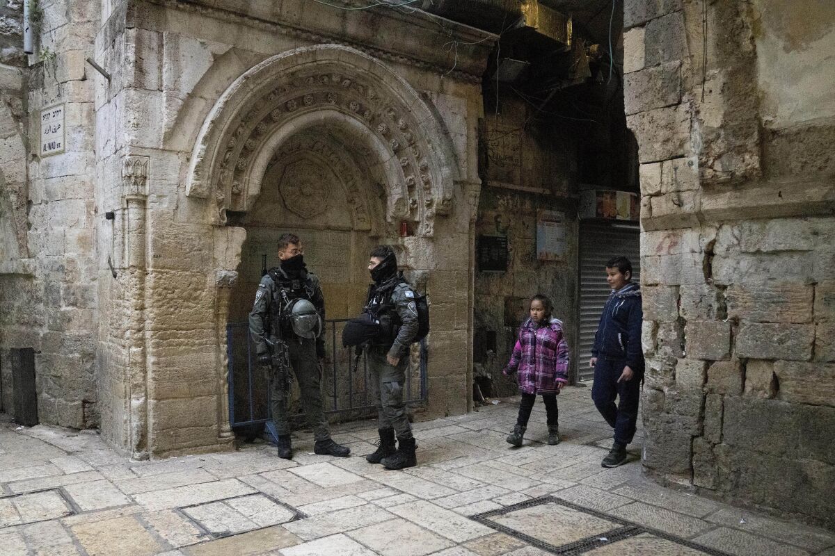 Israeli Border Police stand at their post in the Old City of Jerusalem as Palestinian children walk to school, Sunday, March 6, 2022. Israeli police say officers shot and killed a Palestinian attacker after he stabbed an officer in Jerusalem's Old City. Police identified the attacker as a 19-year-old resident of east Jerusalem. (AP Photo/Maya Alleruzzo)