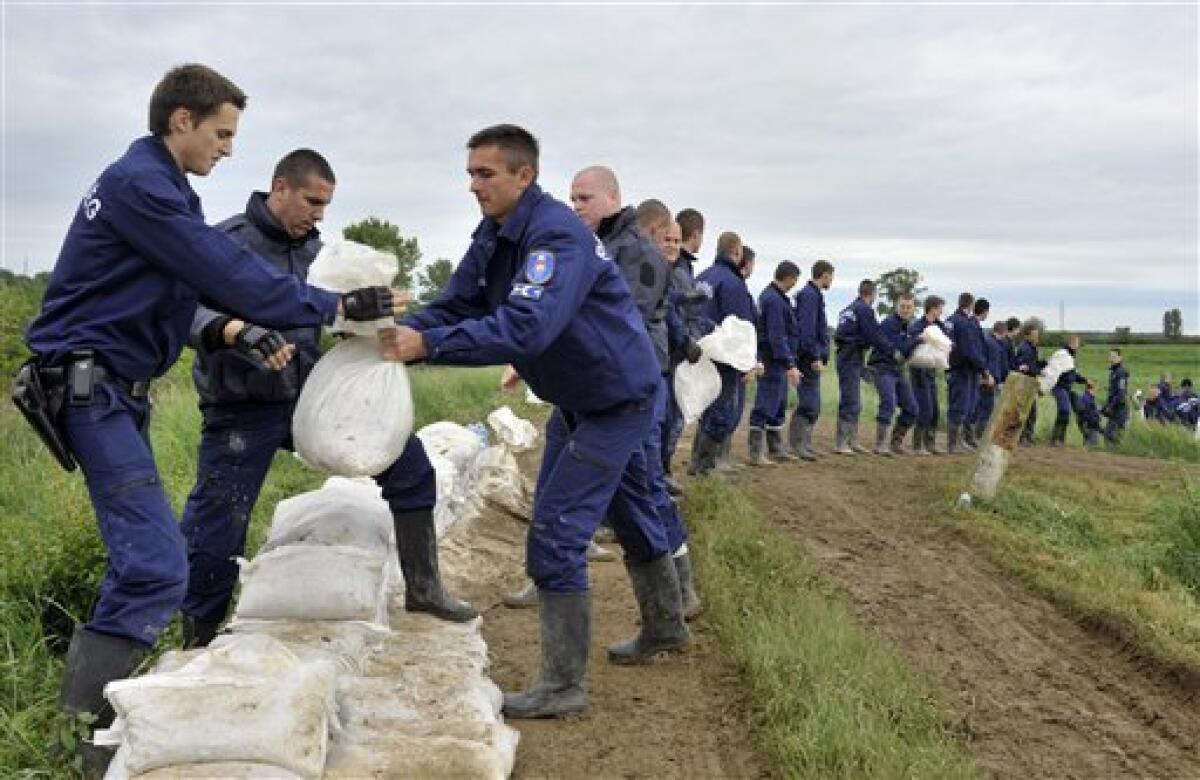 Police officers work in a row while loading sandbags to protect a broken dike from flooding water near the village of Gesztely, northeastern Hungary, Tuesday, May 18, 2010. Several swollen rivers causing floods throughout Hungary, while roads remain closed due to the unusual wet weather and heavy rains. (AP Photo/Bela Szandelszky)