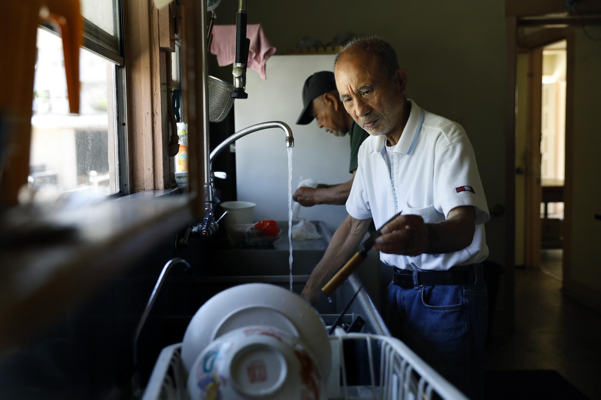 Nobuharu Hamakawa and Hideo Suetake wash dishes after a meal