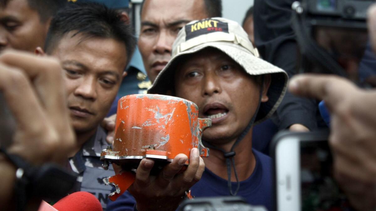 A member of the Indonesian National Commission of Transportation Safety shows the cockpit voice recorder recovered from a Lion Air jet that crashed off Indonesia in 2018.