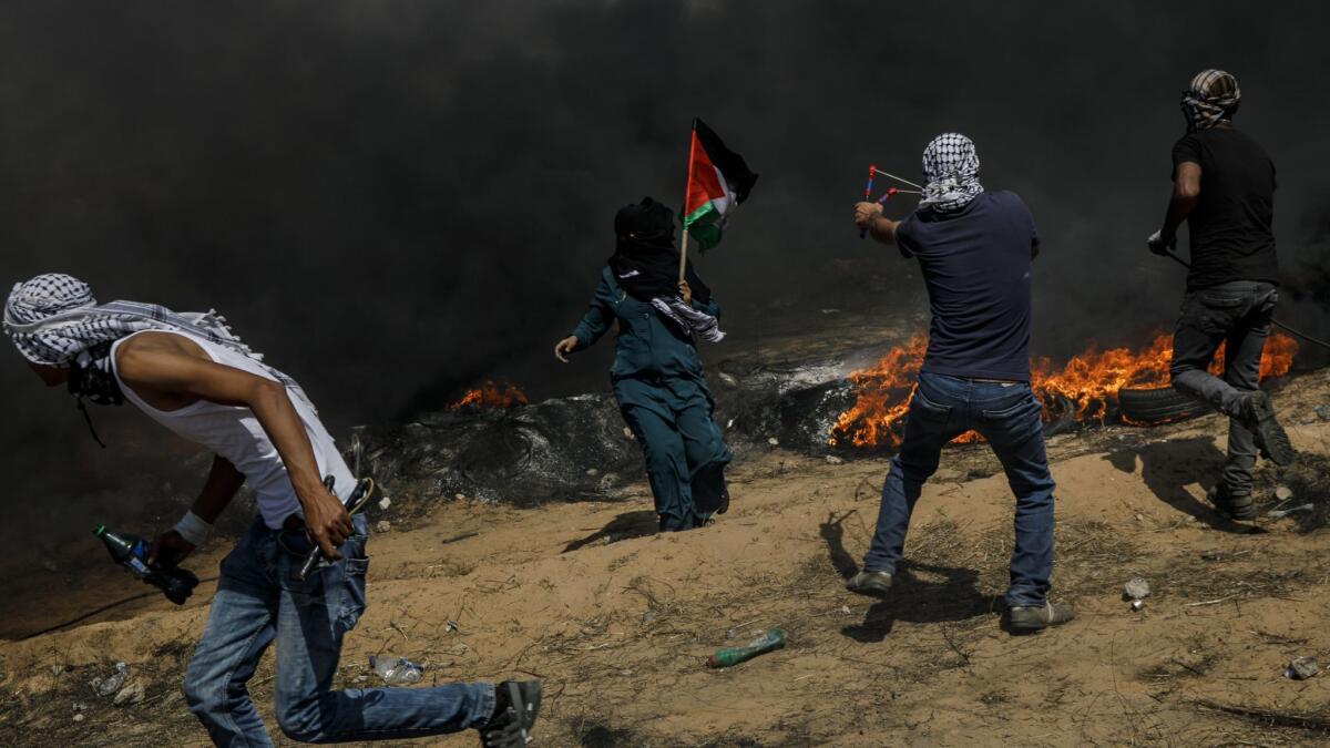 Under the shroud of smoke from flaming tires, Palestinians aim projectiles towards the border fence separating Israel and the Gaza Strip on May 11.