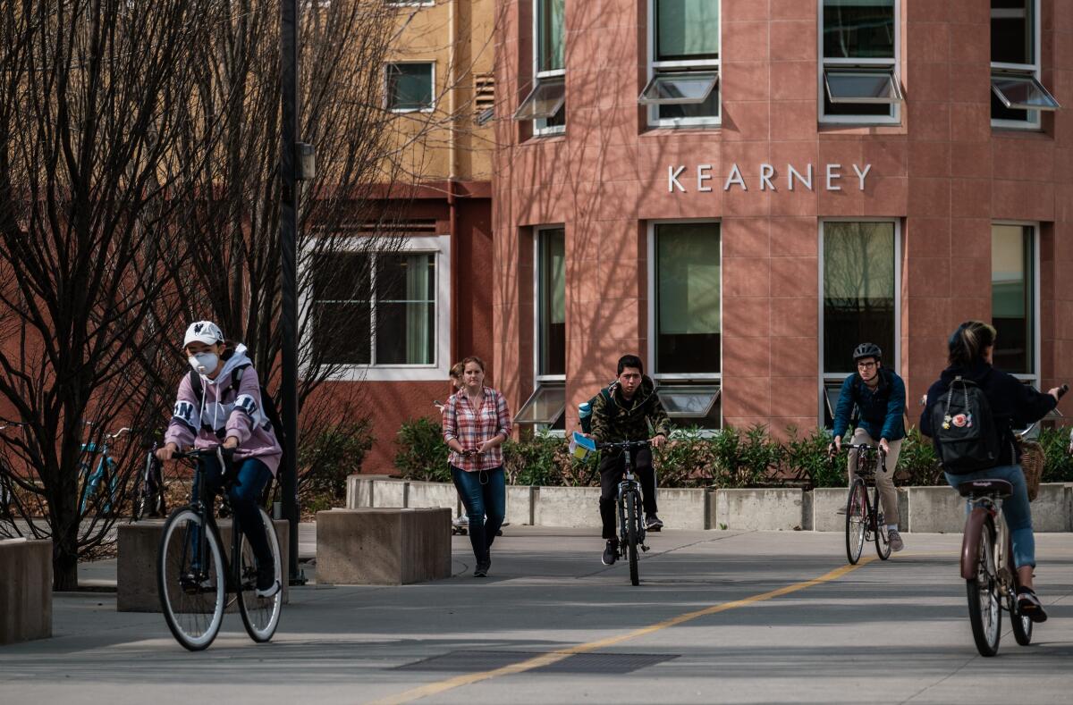 Students ride bikes past Kearney Hall on the UC Davis campus