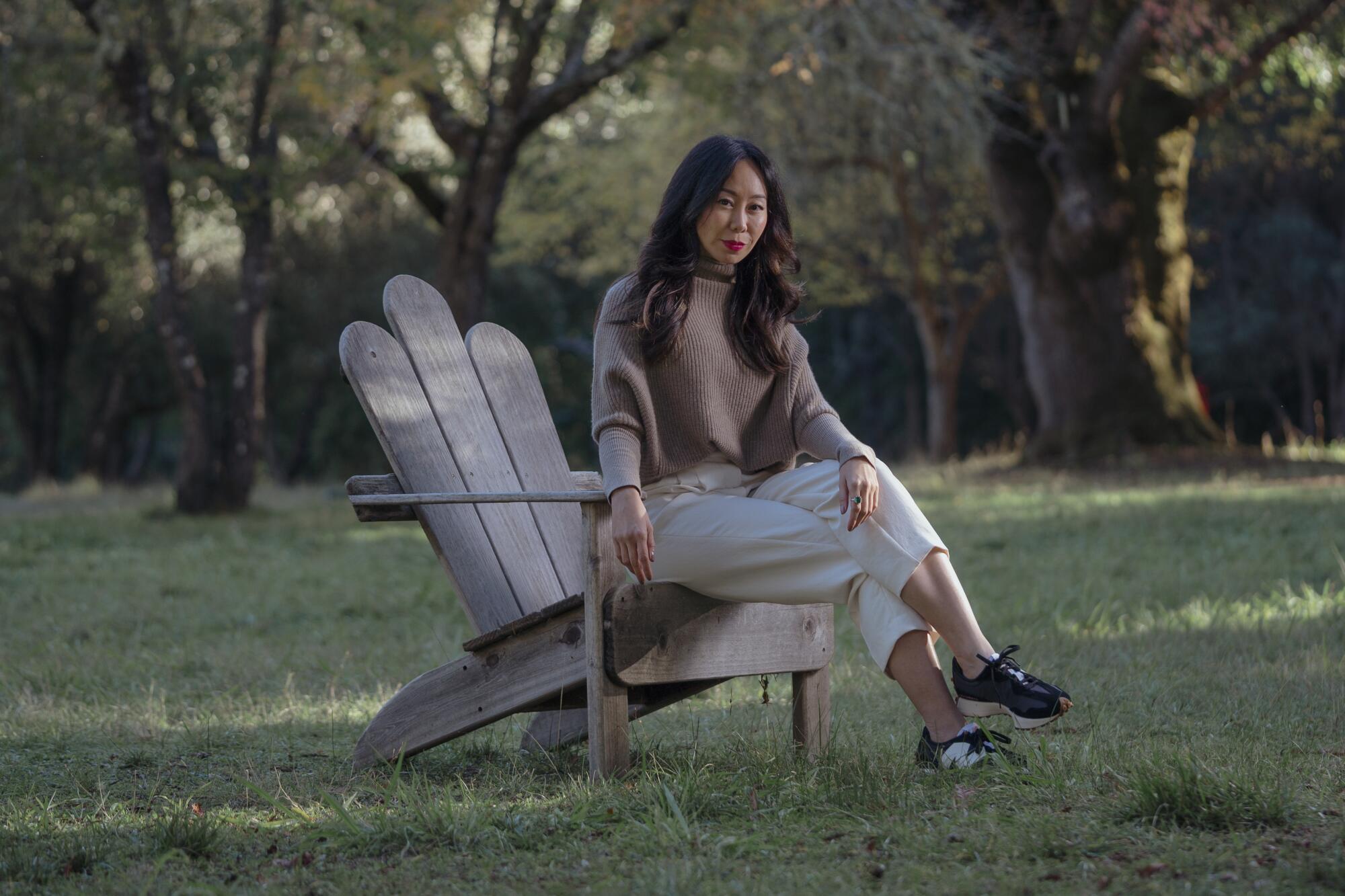 A woman poses in an Adirondack chair outdoors