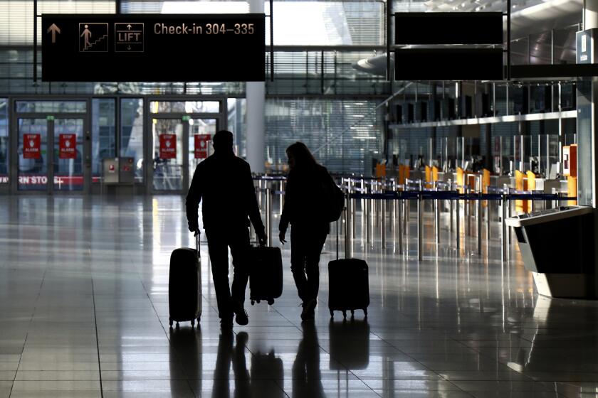 FILE - In this Saturday, Dec. 26, 2020 file photo, people walk with their luggage through a deserted check-in hall at the airport in Munich, Germany as Germany continues its second lockdown to avoid the further outspread of the coronavirus. On Tuesday, Jan. 12, 2021, the U.S. government said it will require airline passengers entering the country to show proof of a negative COVID-19 test before boarding their flights. It will take effect Jan. 26. (AP Photo/Matthias Schrader)