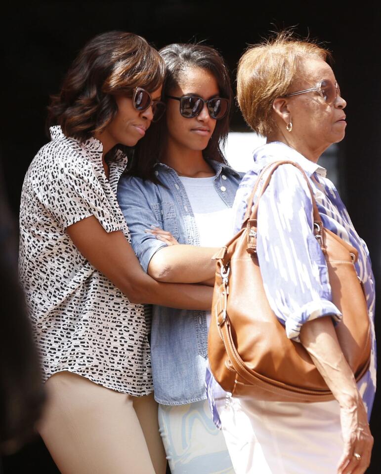 U.S. first lady Michelle Obama hugs her daughter Malia alongside Marian Robinson, Michelle Obama's mother, as they visit the Maison Des Ecslaves on Goree Island