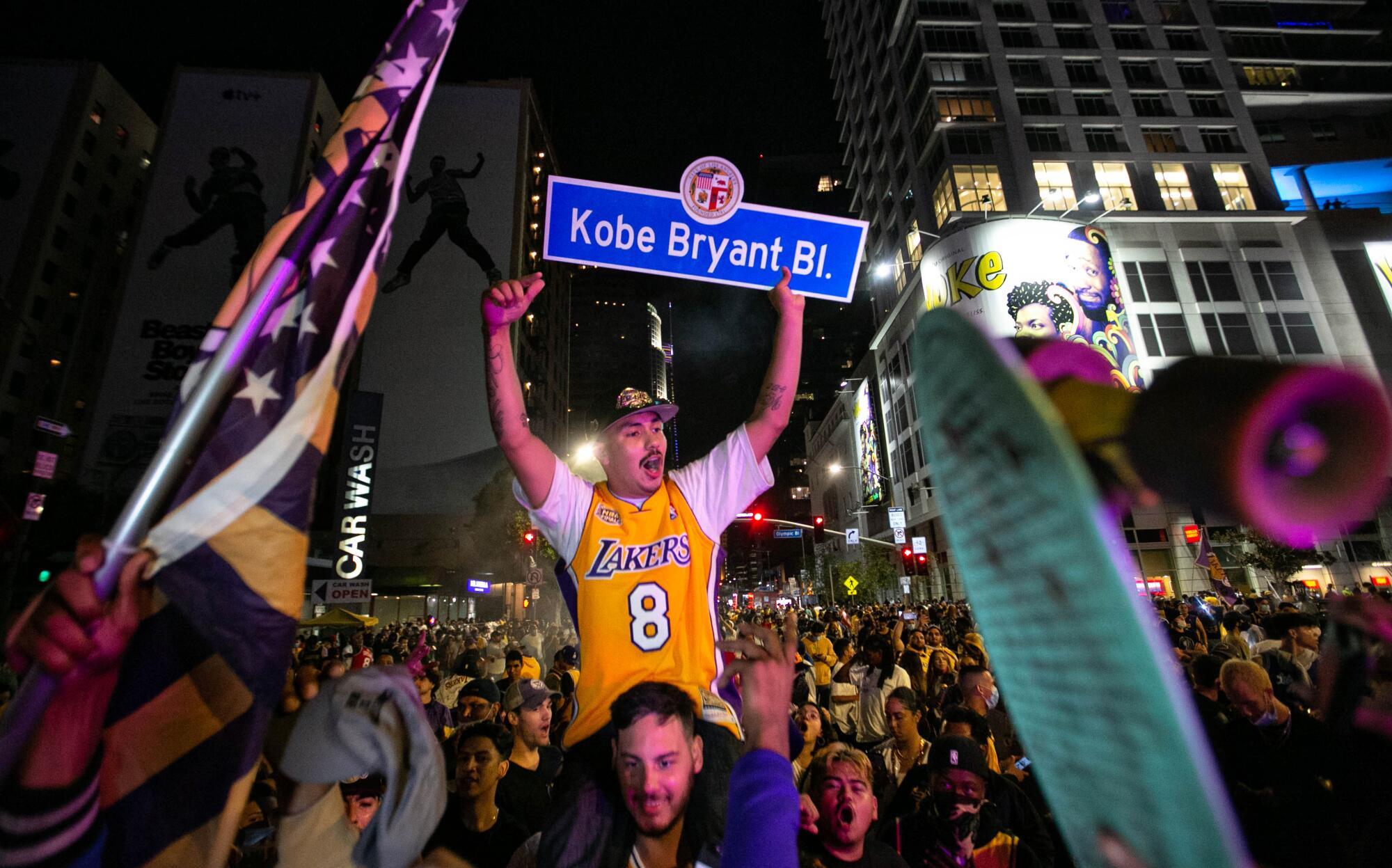 A man holds up a Kobe Bryant Boulevard sign as fans celebrate after the Lakers' win over the Miami Heat in the NBA Finals.