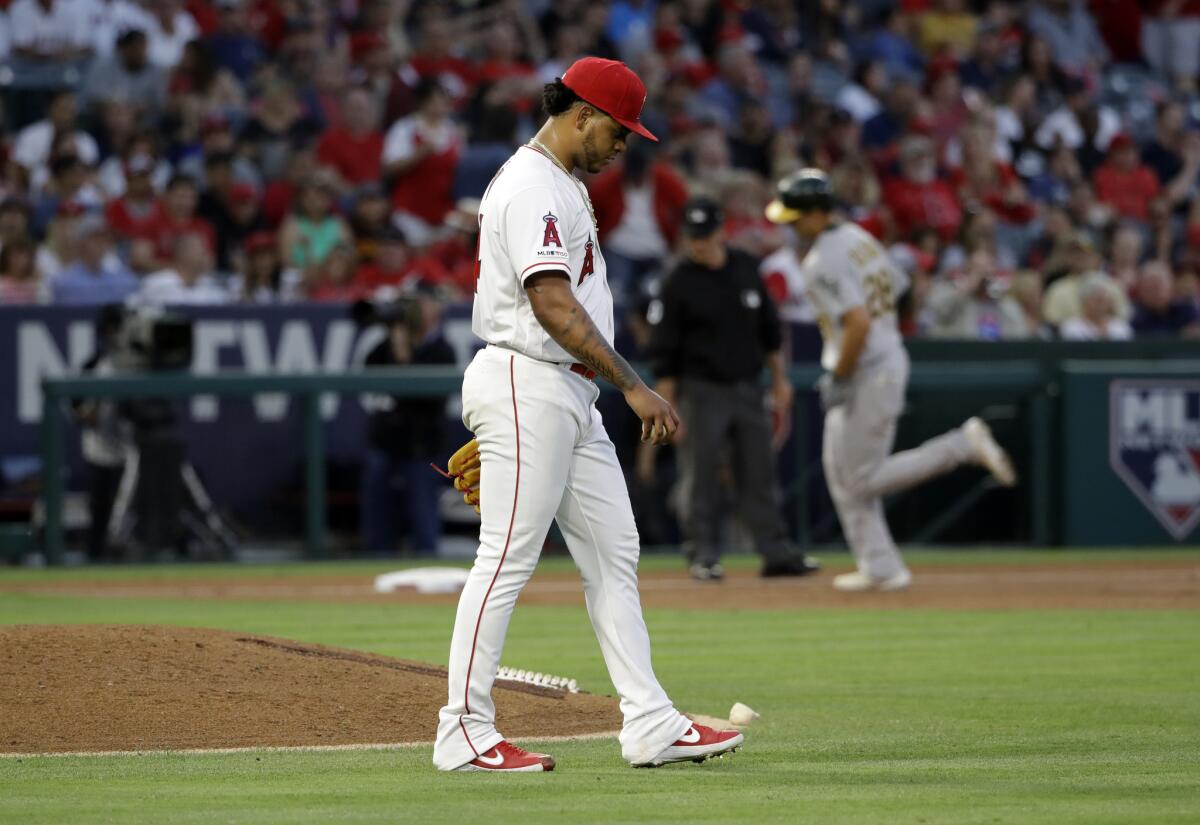 Angels pitcher Felix Pena walks off the mound after giving up a three-run home run to the Athletics' Matt Olson, background right, during the third inning Friday at Angel Stadium.