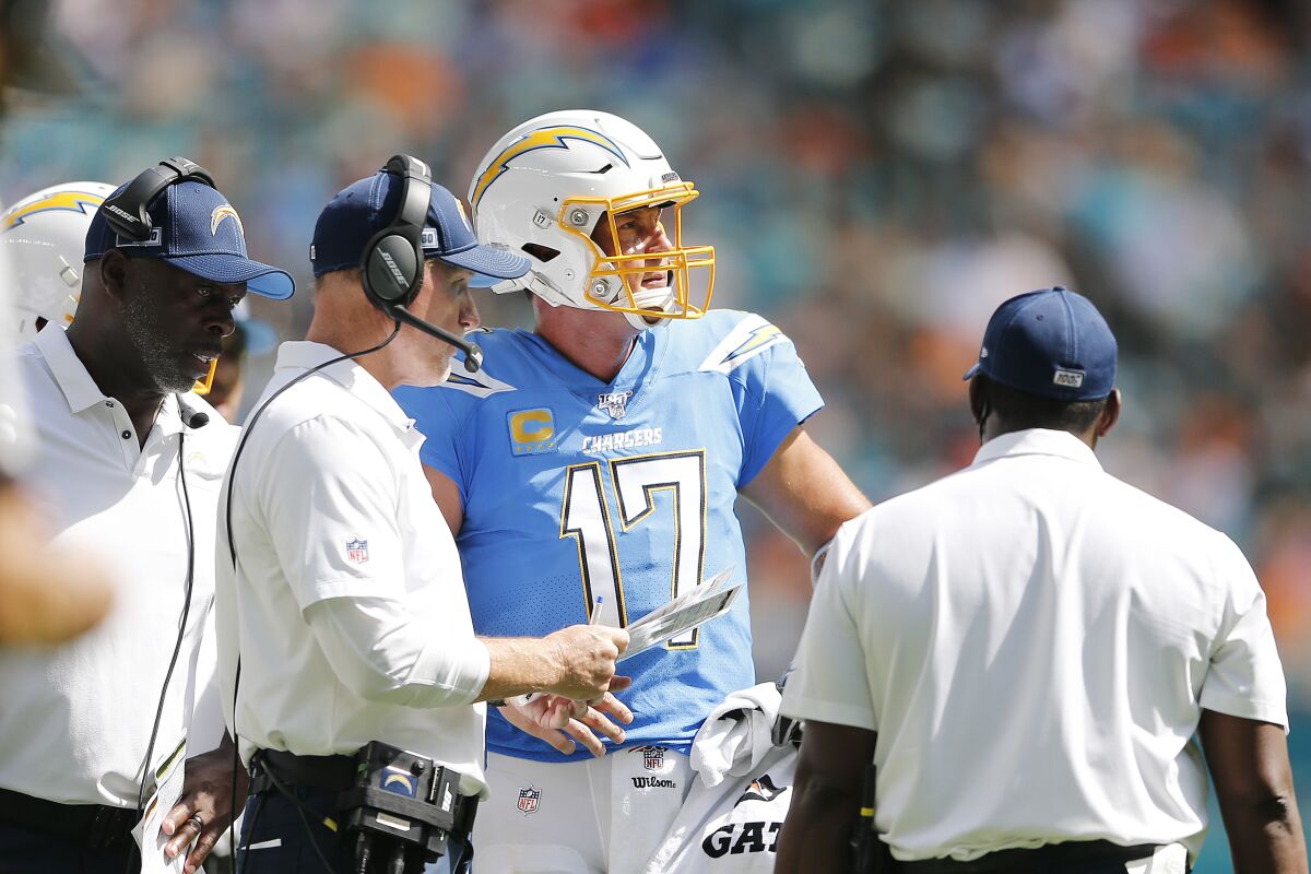Chargers coach Anthony Lynn, left, and offensive coordinator Ken Whisenhunt, center, speak with quarterback Philip Rivers.