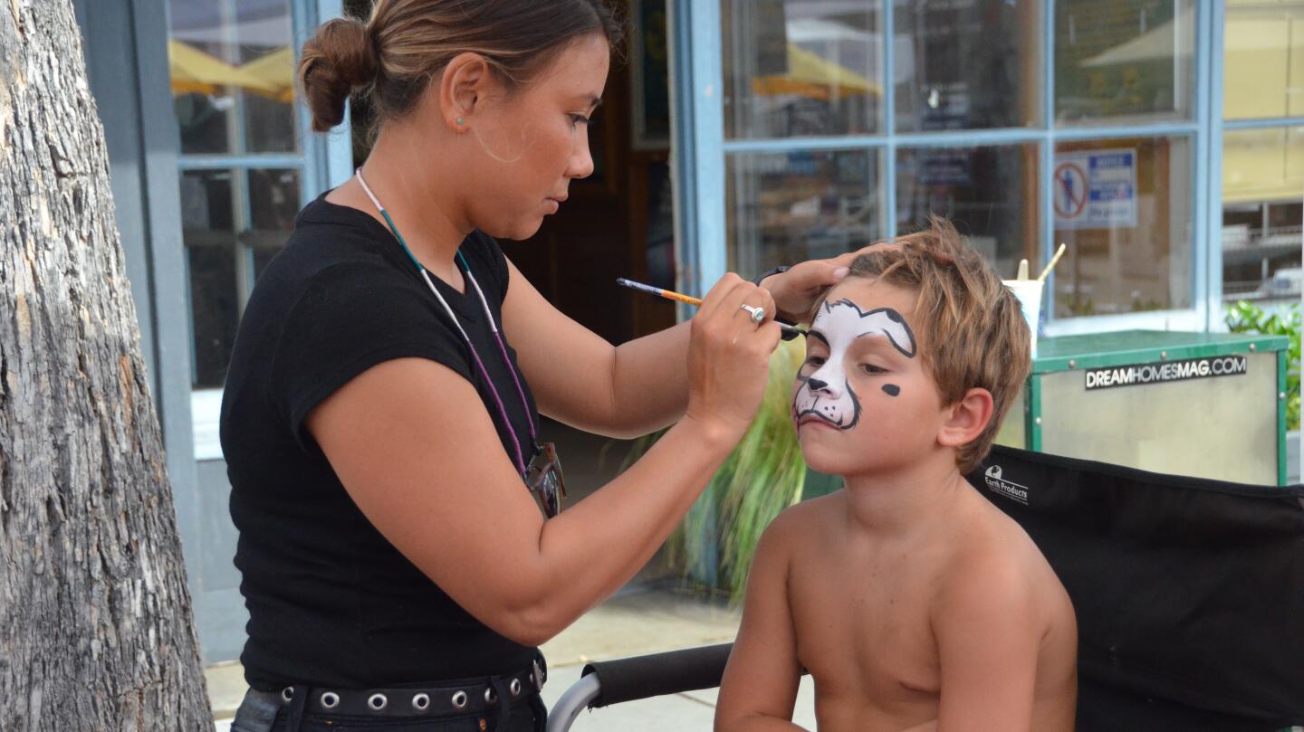 Ryan Dodge, 7, sits still as Angie Steadman applies face paint at the Balboa Island Carnival and & Taste of the Island on Sunday.