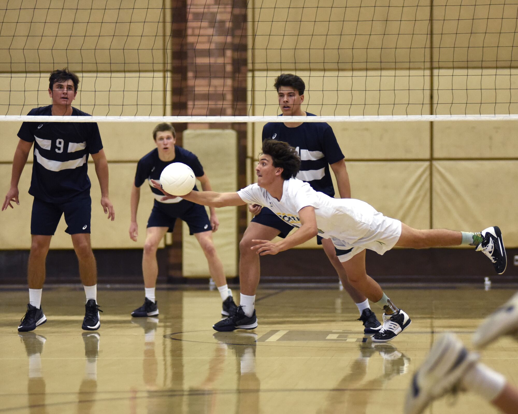 Loyola players watch as Mira Costa's Mira Costa's Jason Walmer Gealon lunges for a dig on March 19, 2022, at Loyola High.