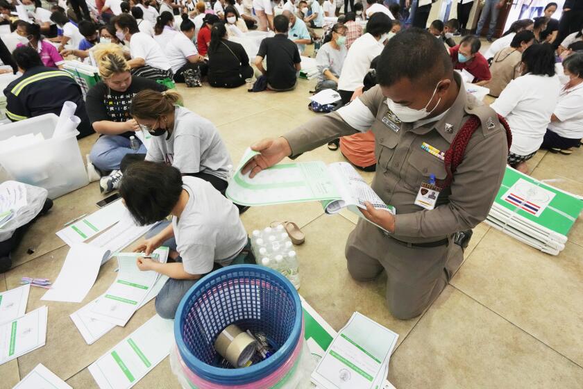 Volunteers and a police officer check ballots for Sunday's general election in Bangkok, Thailand, Saturday, May 13, 2023. (AP Photo/Sakchai Lalit)