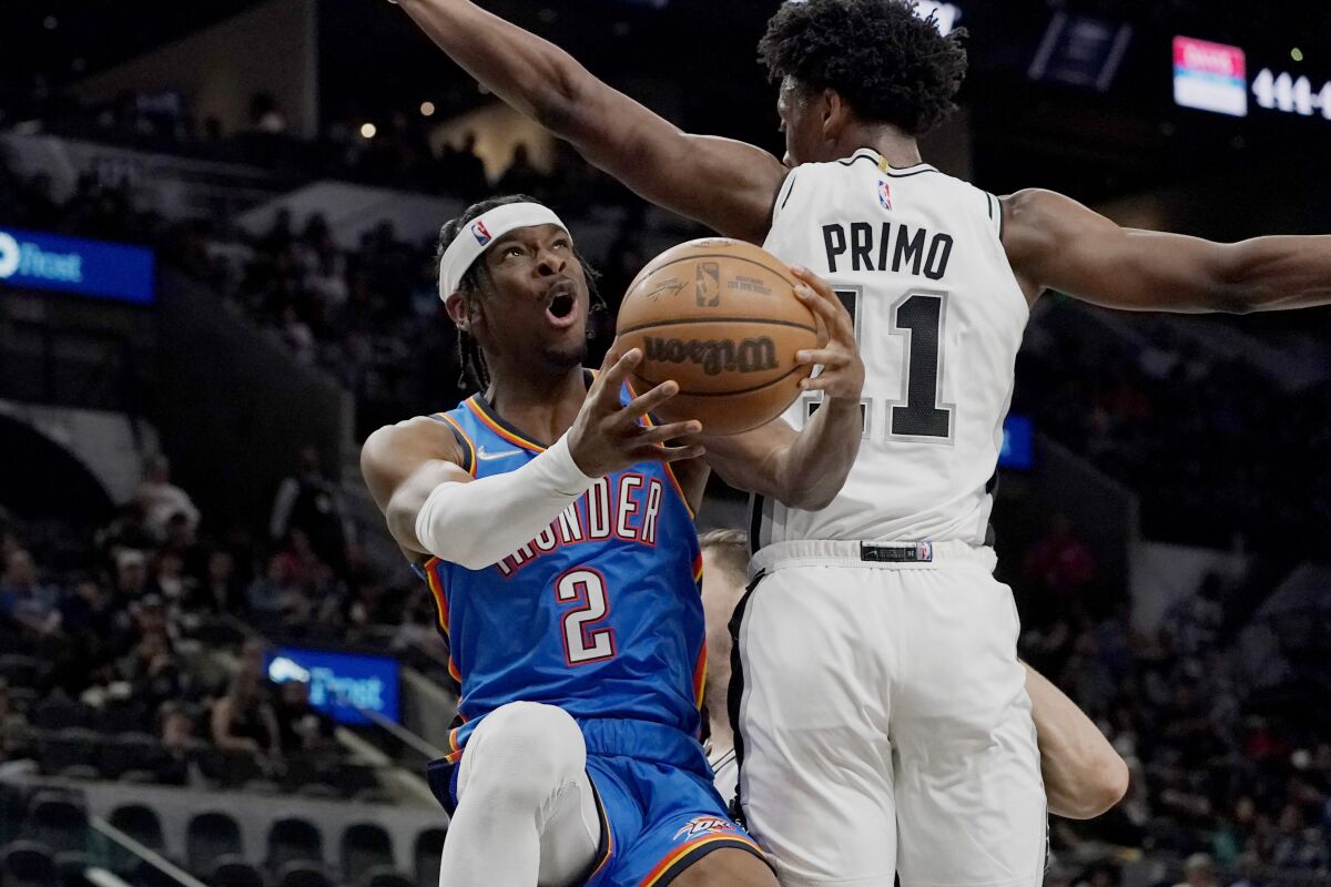 Oklahoma City Thunder guard Shai Gilgeous-Alexander (2) drives to the basket against San Antonio Spurs guard Joshua Primo (11) during the first half of an NBA basketball game, Wednesday, March 16, 2022, in San Antonio. (AP Photo/Eric Gay)