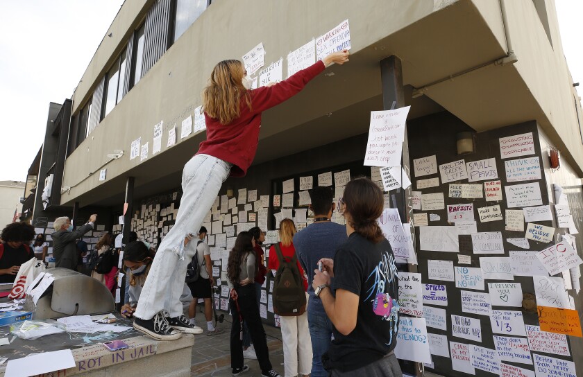 USC junior Bianca Ventola attaches a sign to the Sigma Nu fraternity house.