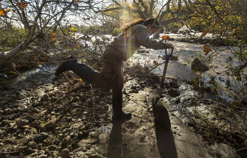 A man dumps water from his boot after helping shovel away mud and debris at Leo Carrillo State Campground in Malibu.