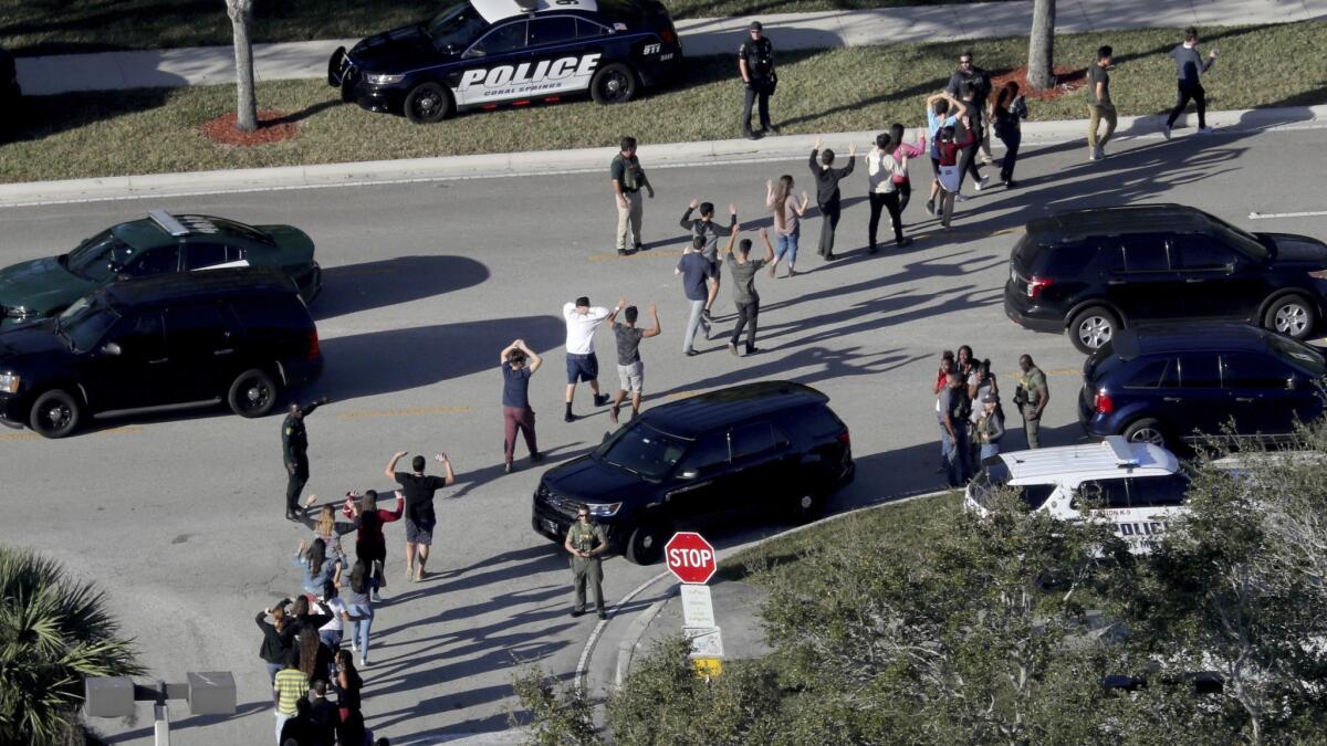 Students hold their hands in the air as they are evacuated by police from Marjory Stoneman Douglas High School in Parkland, Fla., after a shooter opened fire on the campus in February, killing 17 people.