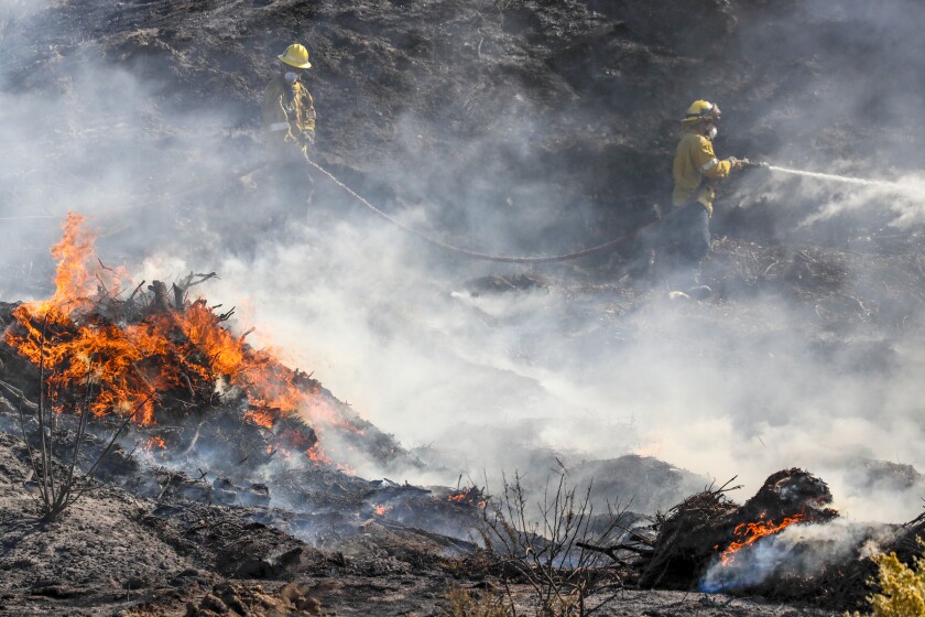 Firefighters battle the Tick fire along Sierra Highway on Friday in Santa Clarita.