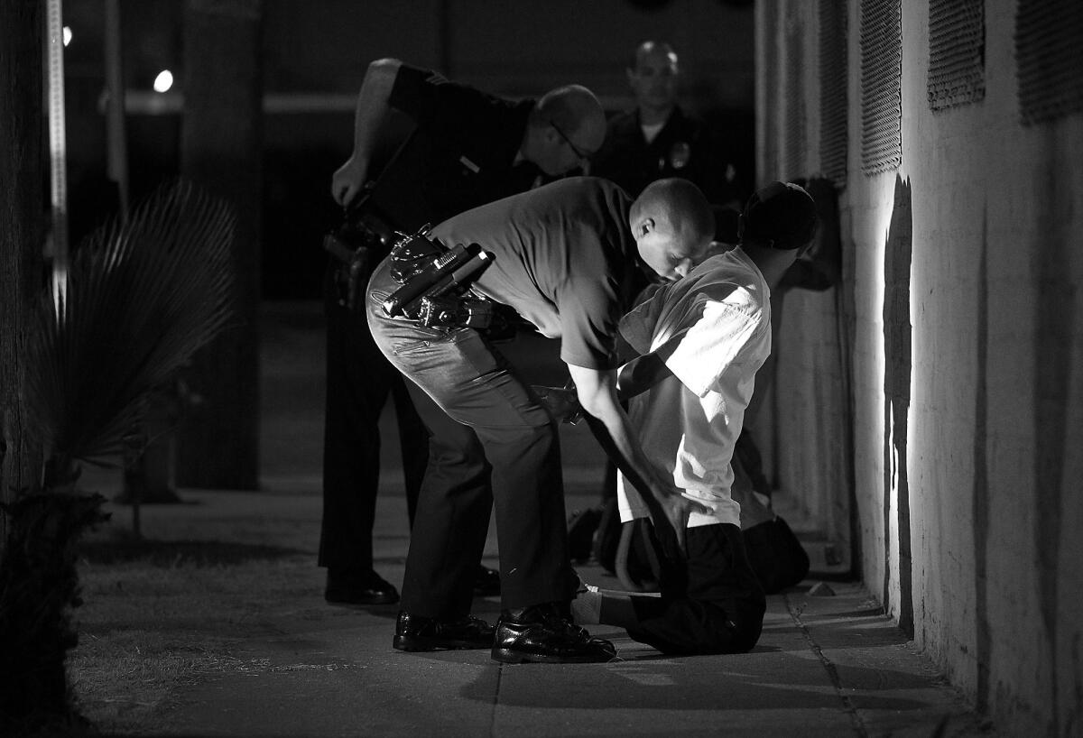 Officer Clay Bell pats down a suspected gang member while on patrol in the Newton Division.