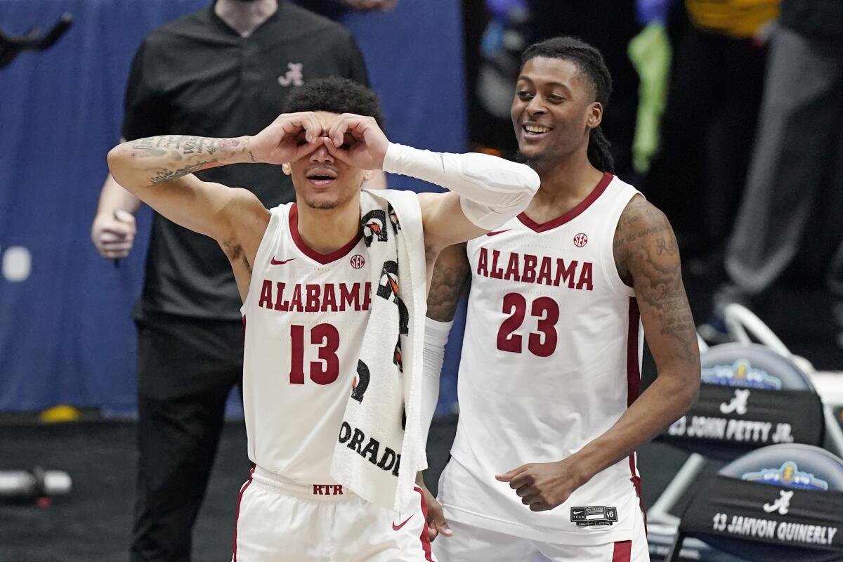 Alabama's Jahvon Quinerly (13) and John Petty Jr. (23) celebrate in the final moments of Alabama's win over Mississippi State in an NCAA college basketball game in the Southeastern Conference Tournament Friday, March 12, 2021, in Nashville, Tenn. (AP Photo/Mark Humphrey)