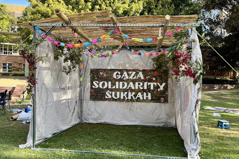 A three-sided tent with bamboo covering and a sign that says "Gaza solidarity Sukkah."