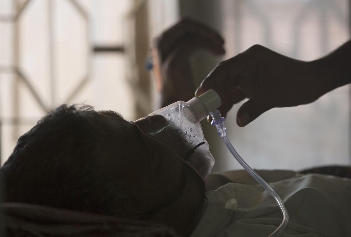 A relative adjusts the oxygen mask of a tuberculosis patient.