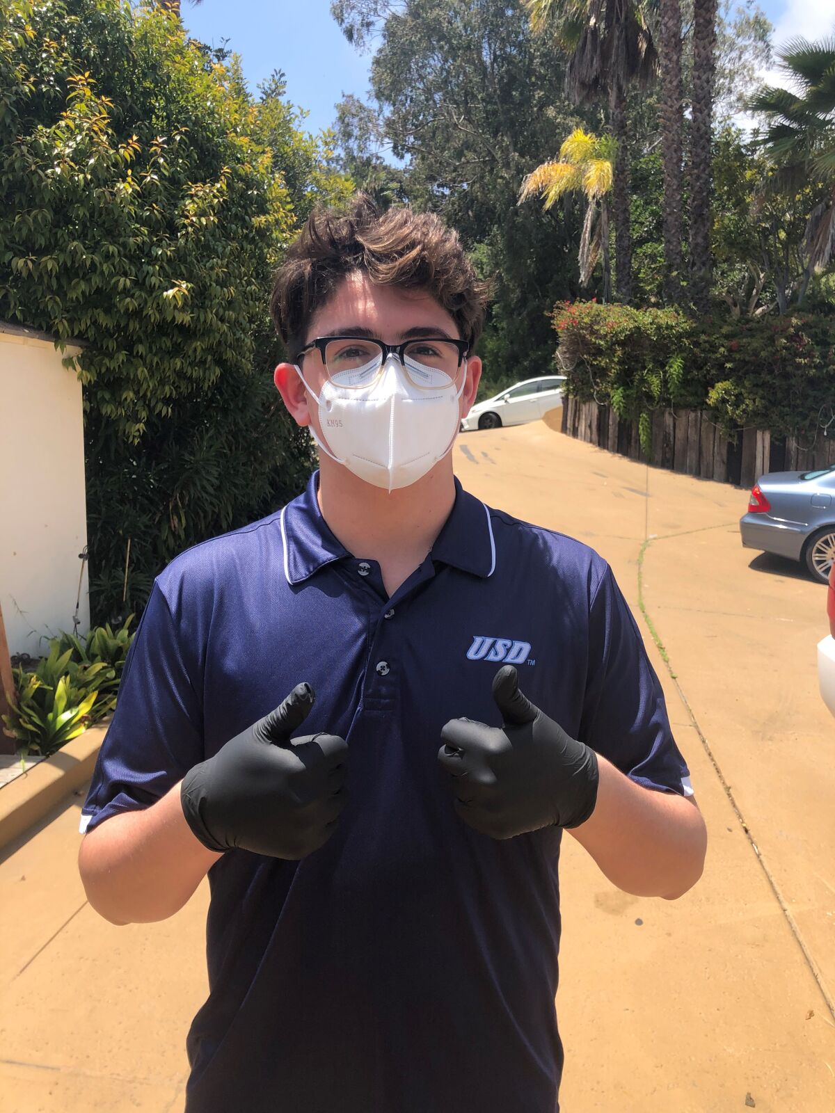 La Jolla High School sophomore Max Stone shows Zoomers to Boomers' shopping and delivery safety precautions, including mask and gloves.