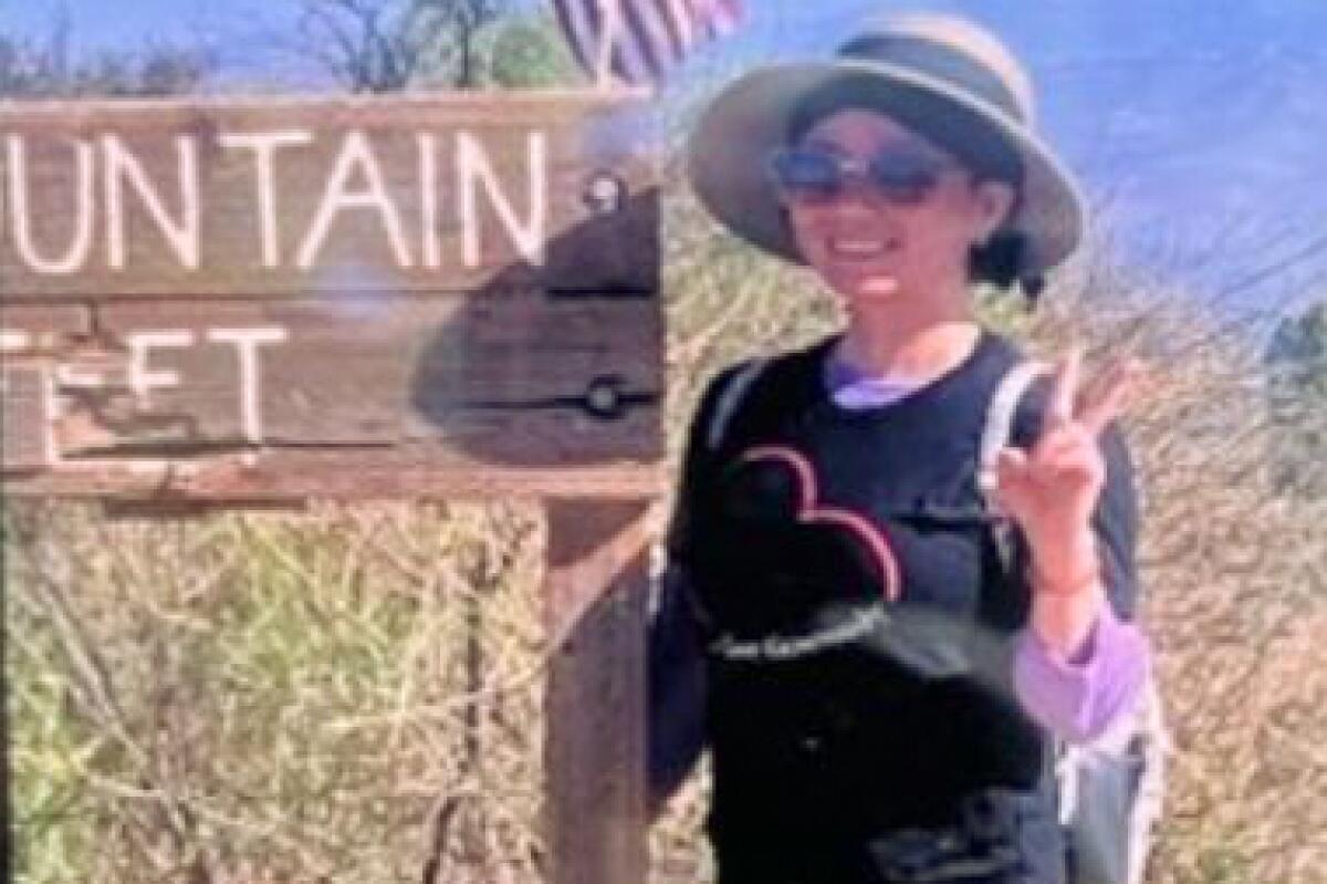 A woman poses next to a trail sign on Black Mountain