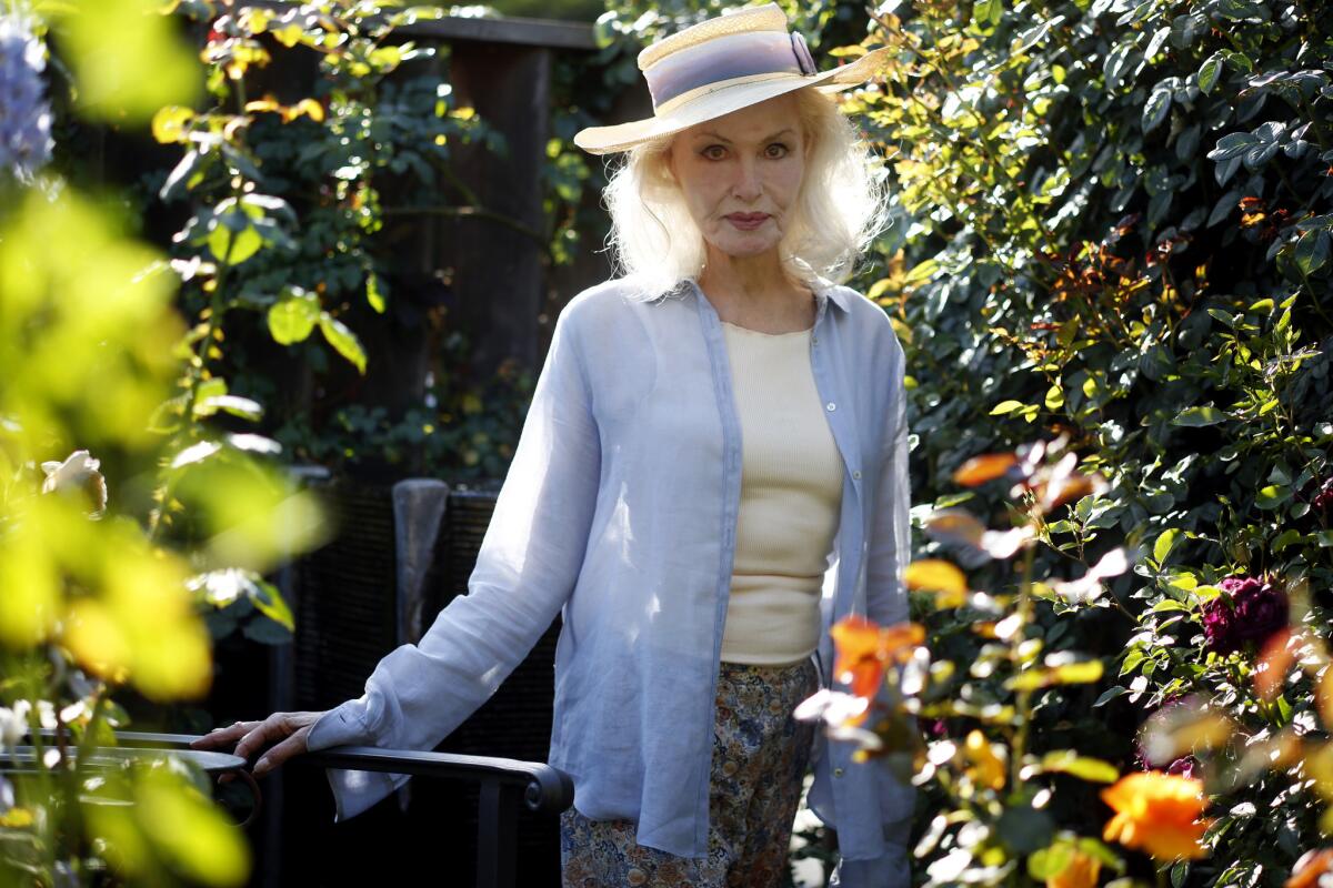 Julie Newmar stands beside the rose named for her. "It's like pale gold dipped in rubies," she says, "and the scent of it is an 11 out of 10."