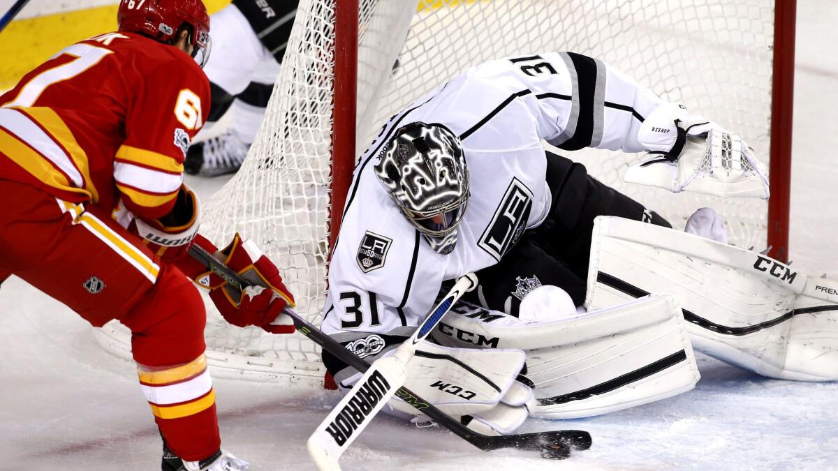 Kings goalie Ben Bishop tries to cover the puck while Flames right wing Michael Frolik tries to control the rebound after save during the third period Wednesday night.