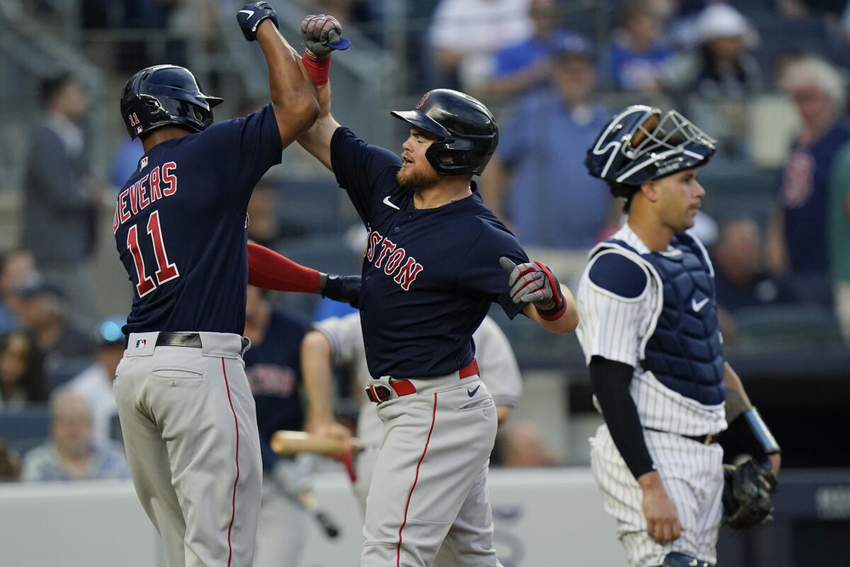 Boston Red Sox's Christian Arroyo, center, celebrates with teammate Rafael Devers, left, as New York Yankees catcher Gary Sanchez, right, looks away during the second inning of a baseball game Friday, July 16, 2021, in New York. (AP Photo/Frank Franklin II)