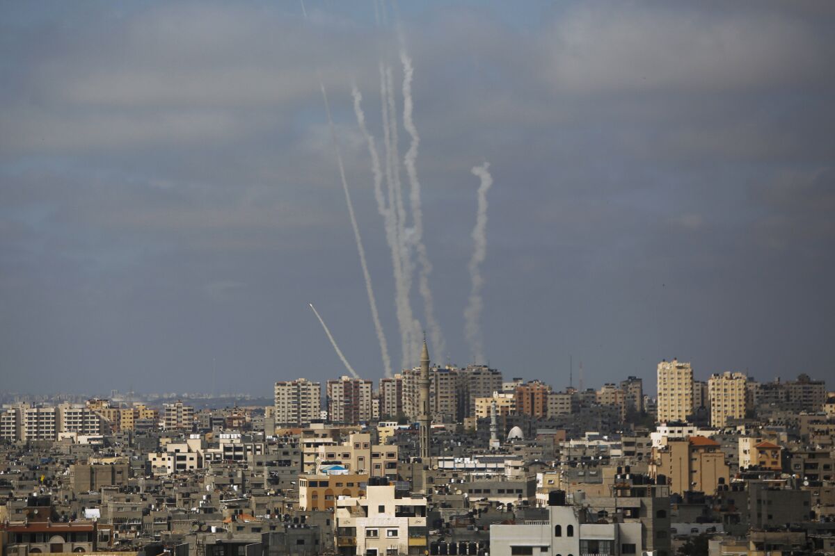 Launch streams from rockets are seen beyond Gaza's towers.