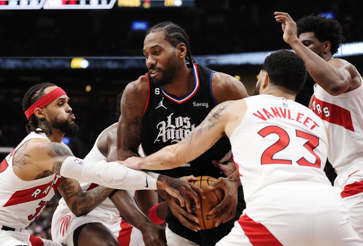 Clippers forward Kawhi Leonard tries to keep the ball from Toronto Raptors guard Gary Trent Jr. and guard Fred VanVleet.