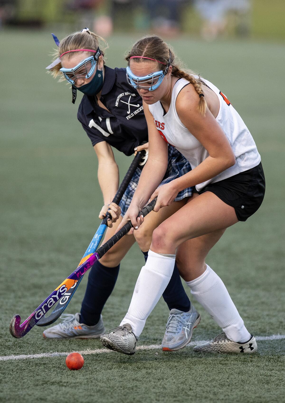 Newport Harbor's Zoe Bixby and Huntington Beach's Avery Wiley battle for a ball during a field hockey match on Friday.