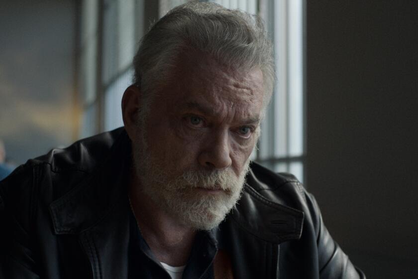 A grizzled looking man in a white beard wearing a leather jacket